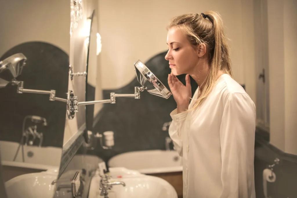 Femme adulte observant dans un miroir les boutons du bas du visage liés à une acné hormonale