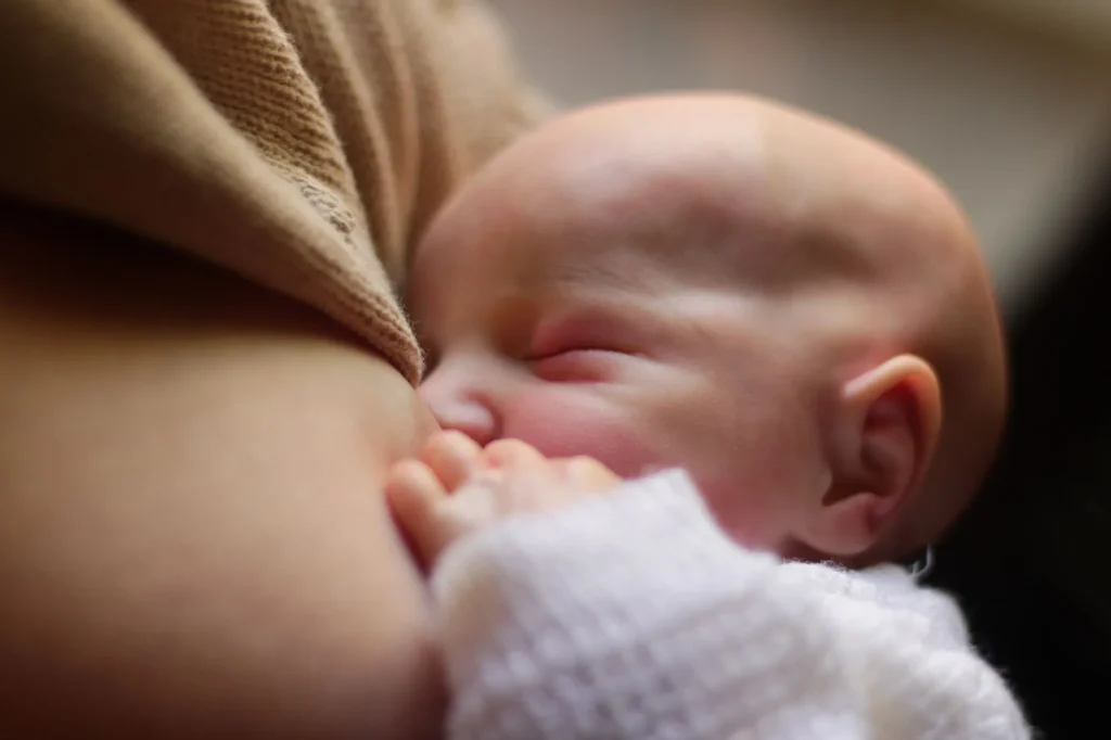 Jeune mère allaitant son nouveau-né pendant le démarrage de l'allaitement, période des premières douleurs