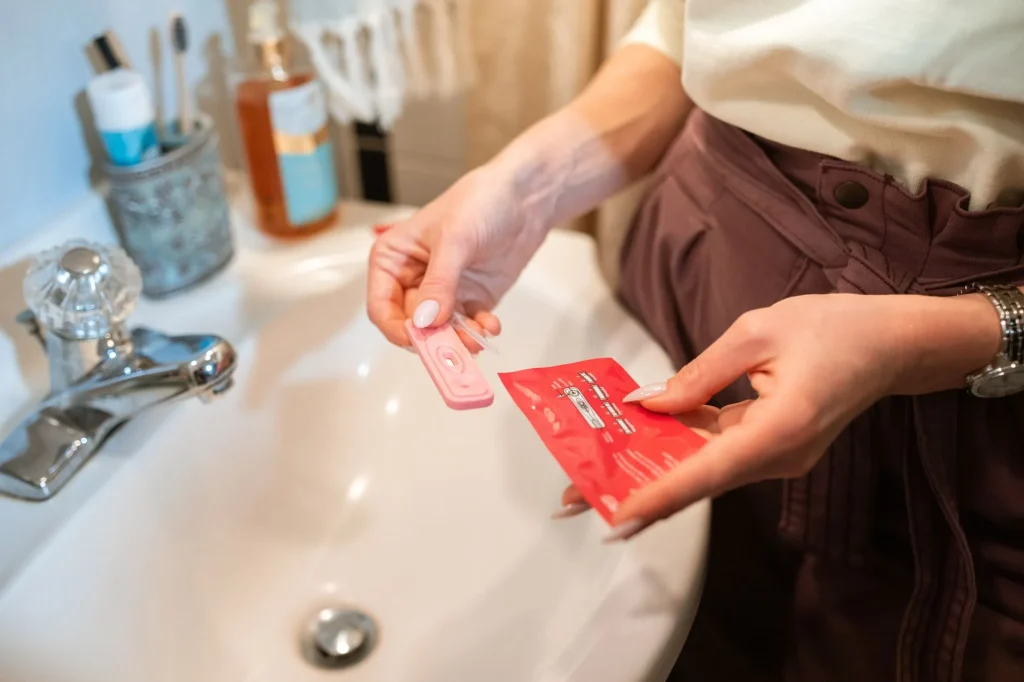 Test de grossesse urinaire tenu en main au moment de lire le résultat